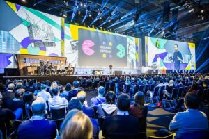 Besucher*innen des OMR Festivals sitzen in einer Halle und folgen einem Vortrag eines Speakers auf der Bühne