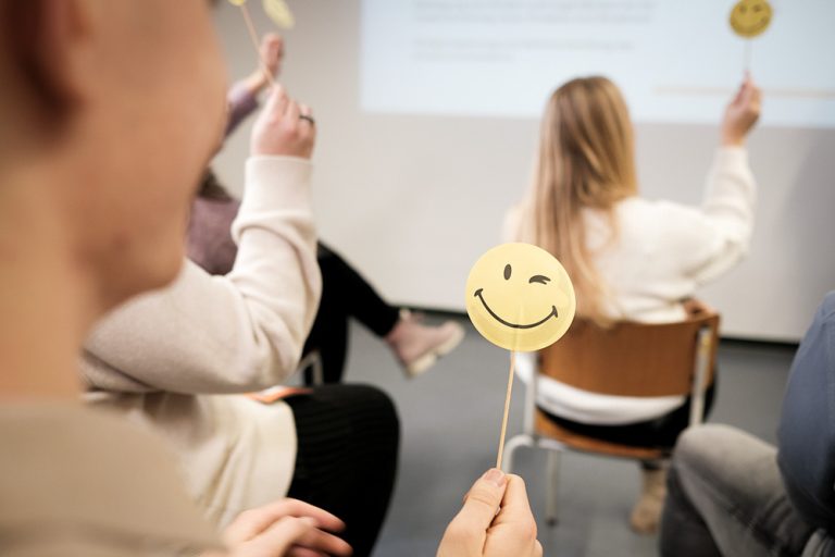 Seminarteilnehmende halten Smileys hoch