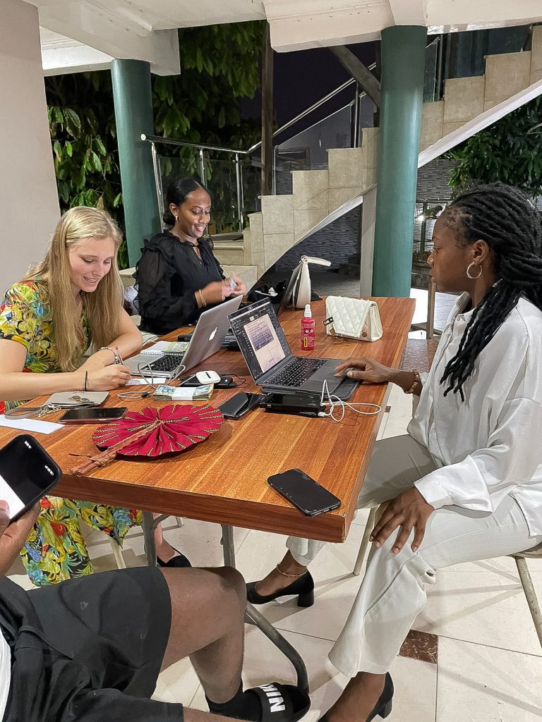 Die Frauen von Glory Healthcare sitzen um einen Tisch und arbeiten an Laptops.