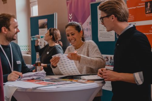 Ein Stand beim Impactday an dem Menschen stehen und lachen.